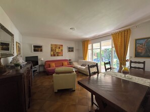 A living room with a sofa, a dining table, and a TV. - St Raphael Garden Villa very nice and quiet close to the beaches and Centre (Saint-Raphaël)