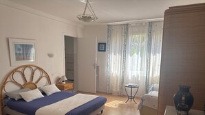 Une chambre à coucher avec un lit, une table de chevet, une lampe et une petite table sur laquelle est posé un vase.