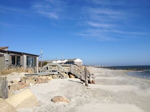 Une structure en bois située au bord de la plage, avec un escalier menant à une zone sablonneuse.