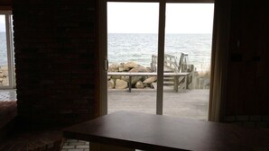 A room with a large sliding glass door leading to a beach view. - Private Sandy Beach, Truly Oceanfront,Private Decks, Free Kayak, Sleeps  5 (South Yarmouth)