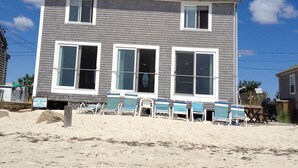 A two-story beach house with a large front porch and a sign indicating it is for rent. - Private Sandy Beach, Truly Oceanfront,Private Decks, Free Kayak, Sleeps  5 (South Yarmouth)