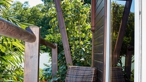 Eine Holzterrasse mit Korbstühlen und einer Glastür, die in einen üppigen Garten führt.