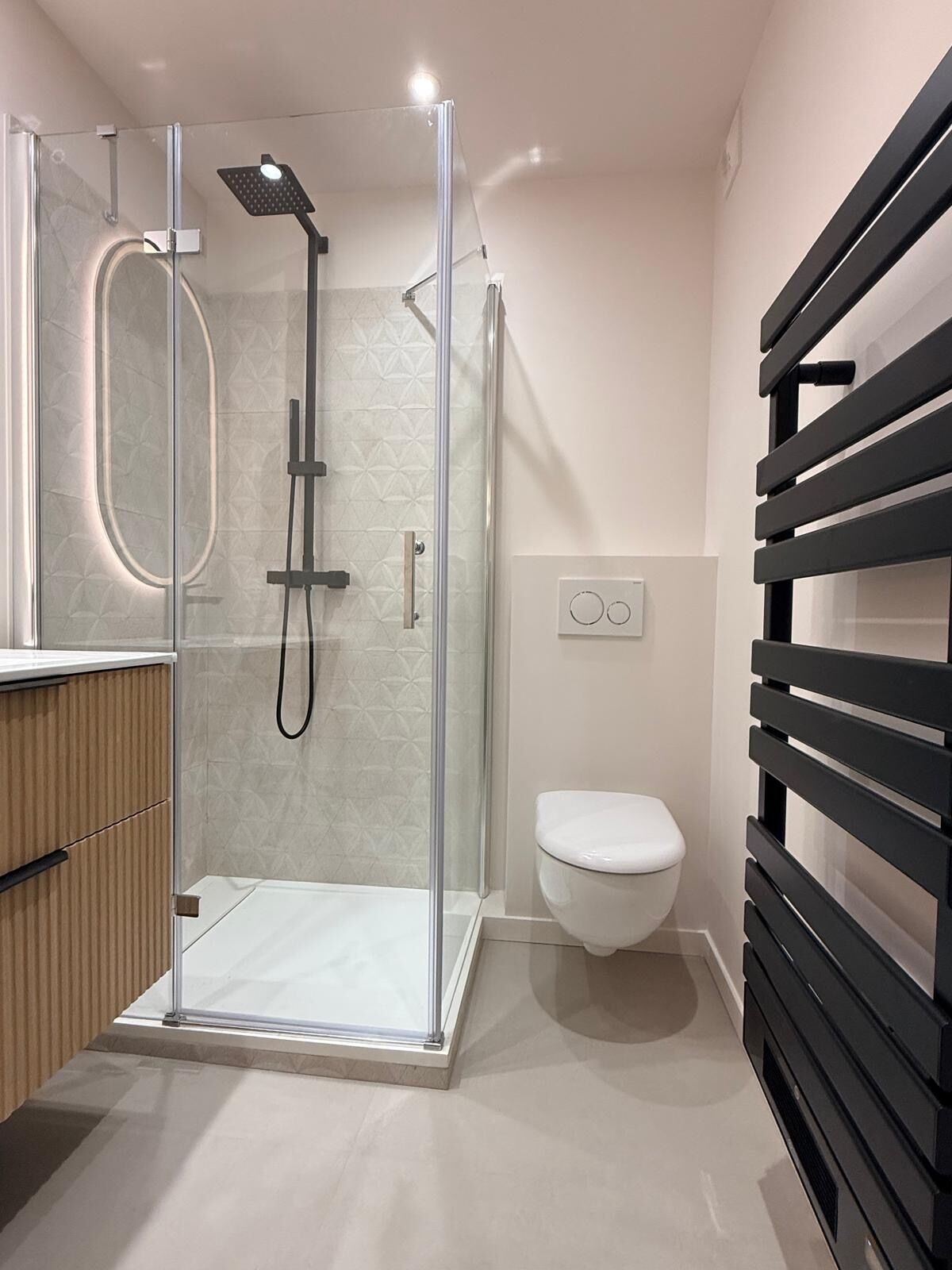 A modern bathroom with a glass-enclosed shower, a toilet, and a wooden vanity.