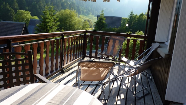 A balcony with a wooden railing, a table, and two chairs. - SUPER LIORAN INDIVIDUAL CHALET COMFORTABLE 8 BEDS (Laveissière)