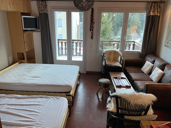 Een kamer met twee bedden, een bank, een stoel, een tafel en een televisie.