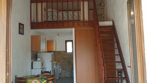 Eine kompakte Küche mit Essbereich, einer Holztreppe und Blick in den Wohnraum.