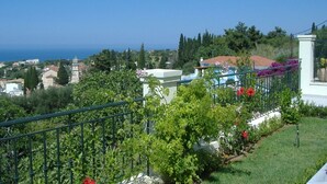 A residential area with a view of the sea, a garden with flowers, and a building with a red roof. - 'Featured in Greece Magazine' Luxury Villa BREATHTAKING SEA VIEWS Kefalonia (Kourkoumelata)