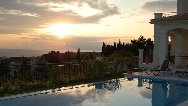A swimming pool with a view of the sea at sunset, a white building with an archway, and a row of trees. - 'Featured in Greece Magazine' Luxury Villa BREATHTAKING SEA VIEWS Kefalonia (Kourkoumelata)