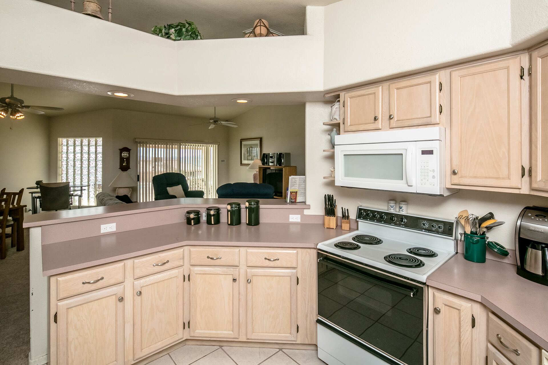 A modern kitchen with a central island, a microwave, a stove, and wooden cabinets.