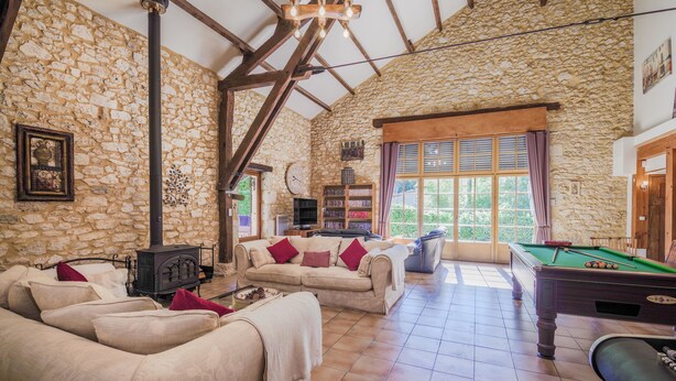 A cozy living room with a stone wall, wooden beams, a fireplace, a pool table, and a sofa with cushions. - ACABANES Luxury Dordogne villas, 20m Bergerac airport, 5m Chateau Vigiers golf (Thénac)
