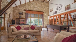 A cozy living room with a stone wall, wooden beams, a pool table, and a sofa. - ACABANES Luxury Dordogne villas, 20m Bergerac airport, 5m Chateau Vigiers golf (Thénac)