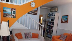 A living room with a staircase, a sofa, a coffee table, a lamp, and a bookshelf. - Burriana Beach 4 Mins Walk, Spanish Town House, 2 Pools - Gardens, WIFI, Air-Con (Burriana, Malaga)