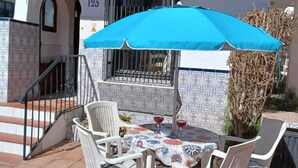 A patio with a table and chairs, a blue umbrella, and a tiled floor. - Burriana Beach 4 Mins Walk, Spanish Town House, 2 Pools - Gardens, WIFI, Air-Con (Burriana, Malaga)