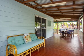 A covered porch with a wicker sofa, a dining table with chairs, and a sliding glass door leading to a covered area.