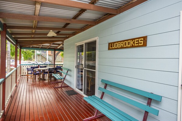 A covered porch with wooden flooring, outdoor seating, and a sign reading "LUOBROOKES".