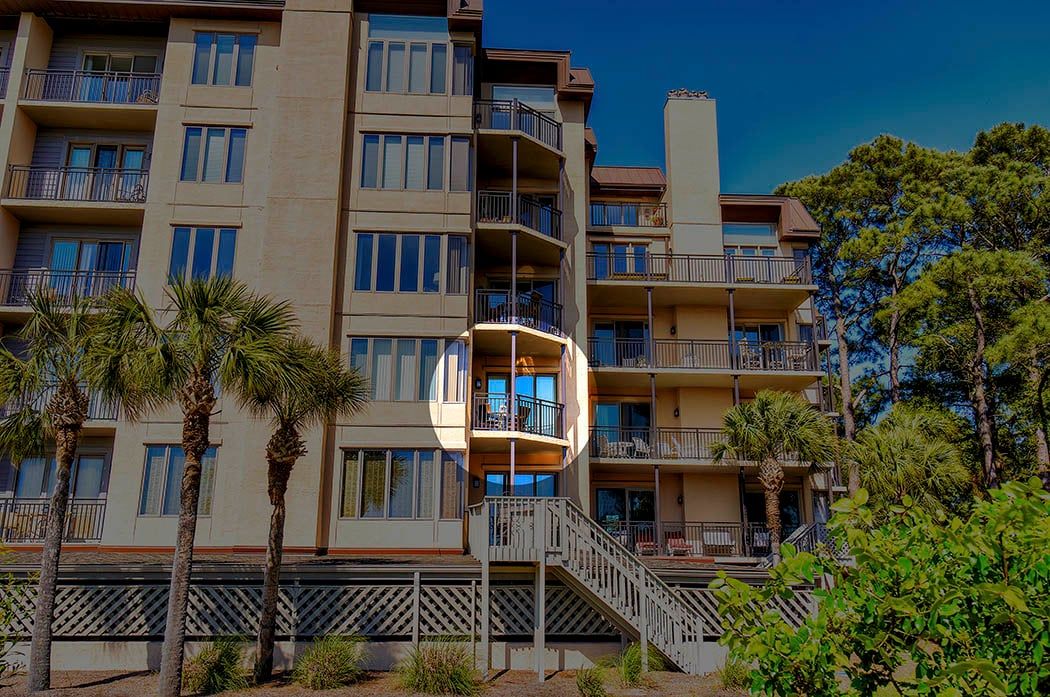 A multi-story hotel with balconies, palm trees, and a clear sky.