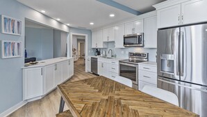 Una cocina moderna con armarios blancos, electrodomésticos de acero inoxidable y piso de madera.