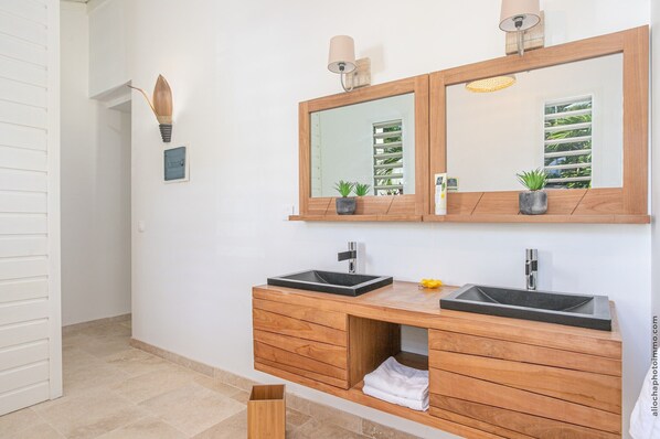 A modern bathroom with two sinks, wooden vanity, and a large mirror.