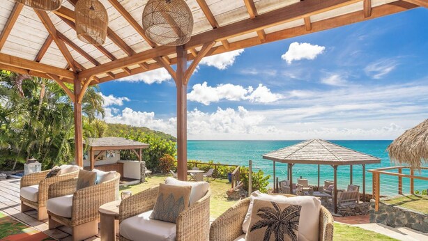 A covered outdoor seating area with wicker furniture and a view of the ocean. - La Sirène du Diamant ,18 guests
Spacious beachfront rental in Martinique : (LE DIAMANT)