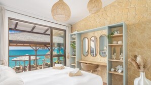 A bedroom with a large bed, a view of the ocean, a stone wall, and a wooden desk with shelves. - La Sirène du Diamant ,18 guests
Spacious beachfront rental in Martinique : (LE DIAMANT)