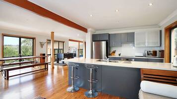 A modern kitchen with a large island, grey cabinets, and stainless steel appliances.