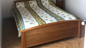 A bedroom with a wooden bed, a white ceiling, and a hanging light fixture. - old house in the heart of sallertaine, garden, shopping on foot (Sallertaine)