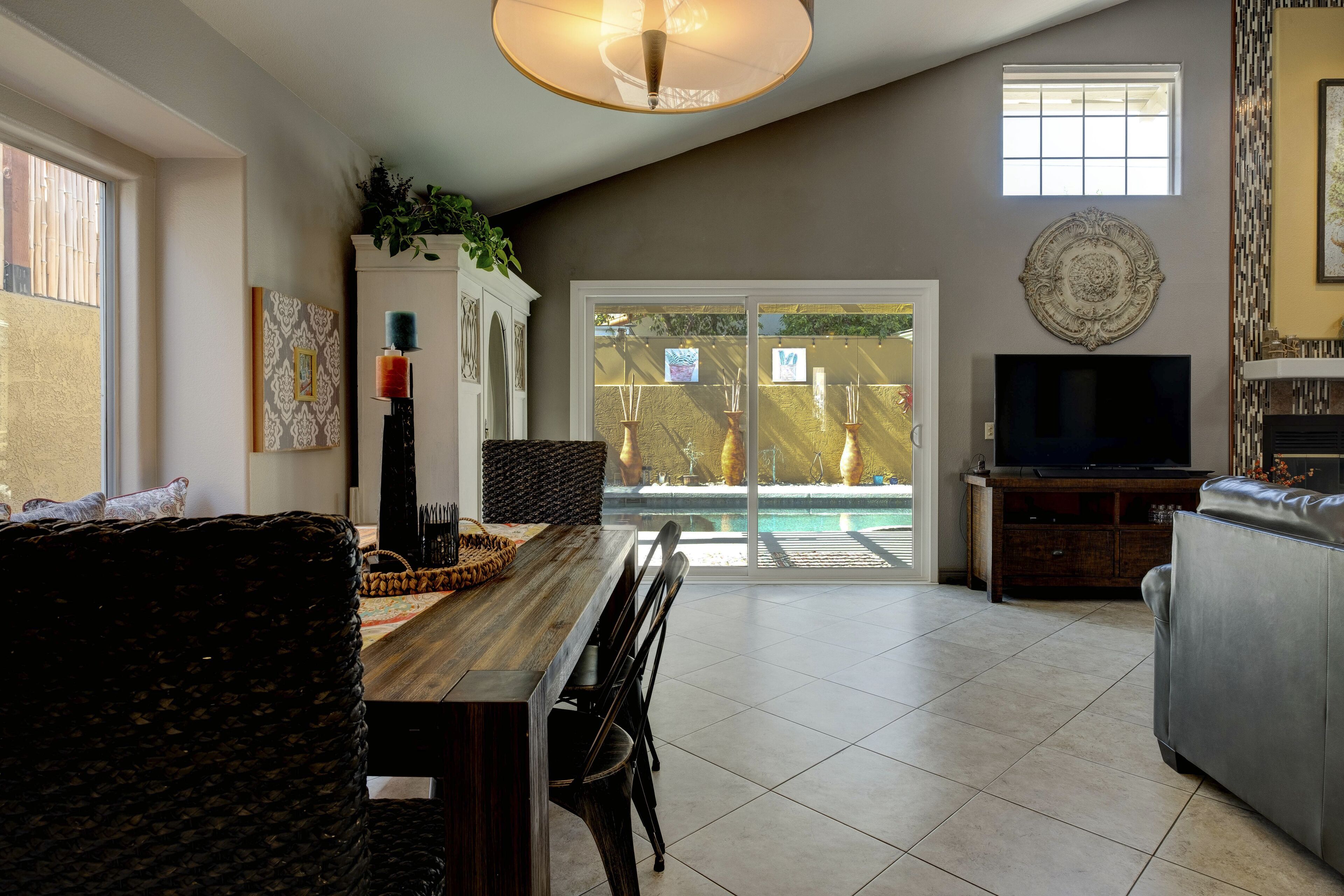 Amplia sala de estar con comedor, chimenea, televisor y vista a una piscina.