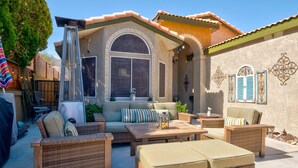 Un patio al aire libre con mobiliario de mimbre, una zona de estar techada y una pared decorativa.