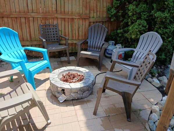 Un patio con sillas Adirondack, un hogar a fuego de piedra y una valla de madera.
