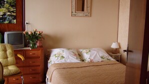 Un dormitorio con cama, cómoda, silla, televisor y espejo.