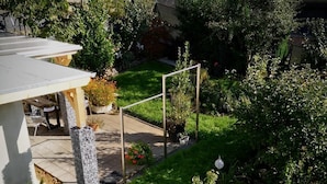 Un jardín en la azotea con diversas plantas, un pérgola y una zona de estar.