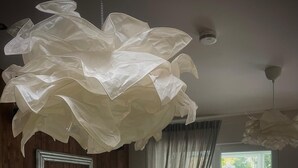 Una sala de estar moderna con un sofá de cuero negro, una mesita redonda y una gran lámpara de araña blanca.