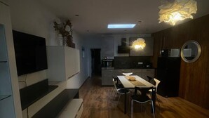 Una cocina moderna con comedor, suelo de madera y televisor empotrado.