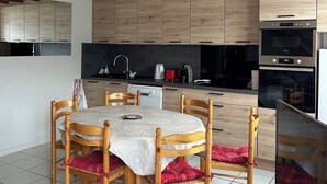 A modern kitchen with wooden cabinets, a dining table with chairs, and a built-in oven. - Cauterets : 6 person chalet - 65 m2 5 mn from town center, 30 mn from Lourdes  (Cauterets)