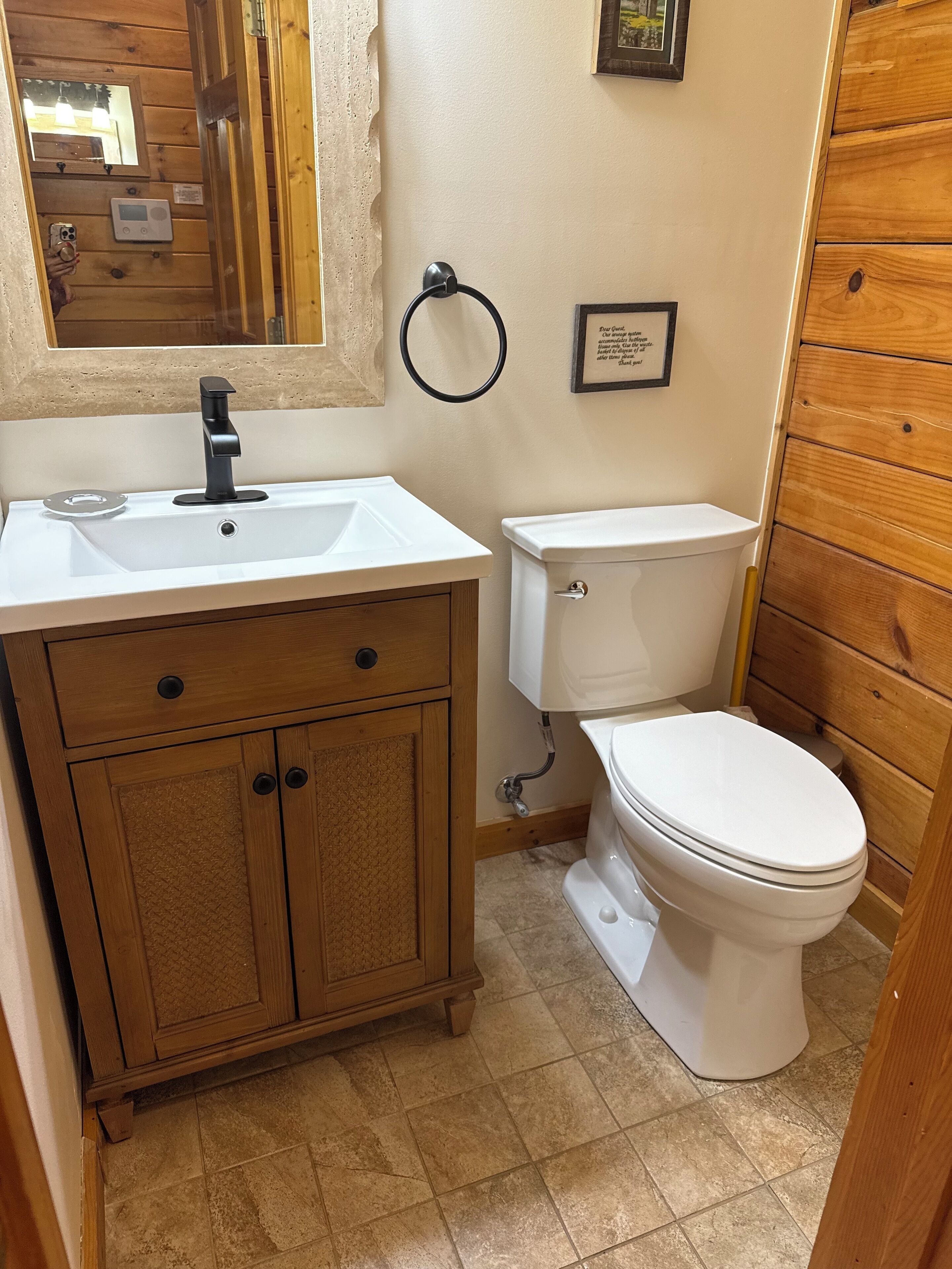 Une salle de bain avec un meuble-lavabo en bois, un lavabo blanc, des toilettes et un miroir.