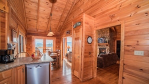 Interior de una cabaña de madera con cocina, comedor y sala de estar.