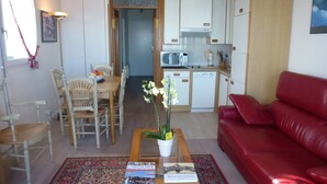 Ett kompakt bostadsutrymme med en matplats, ett kök och en röd soffa.