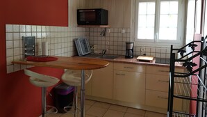 A compact kitchen with a microwave, coffee maker, and a small dining area with stools. - Charming quiet apartment in Villa with garden (Cambo-Les-Bains)