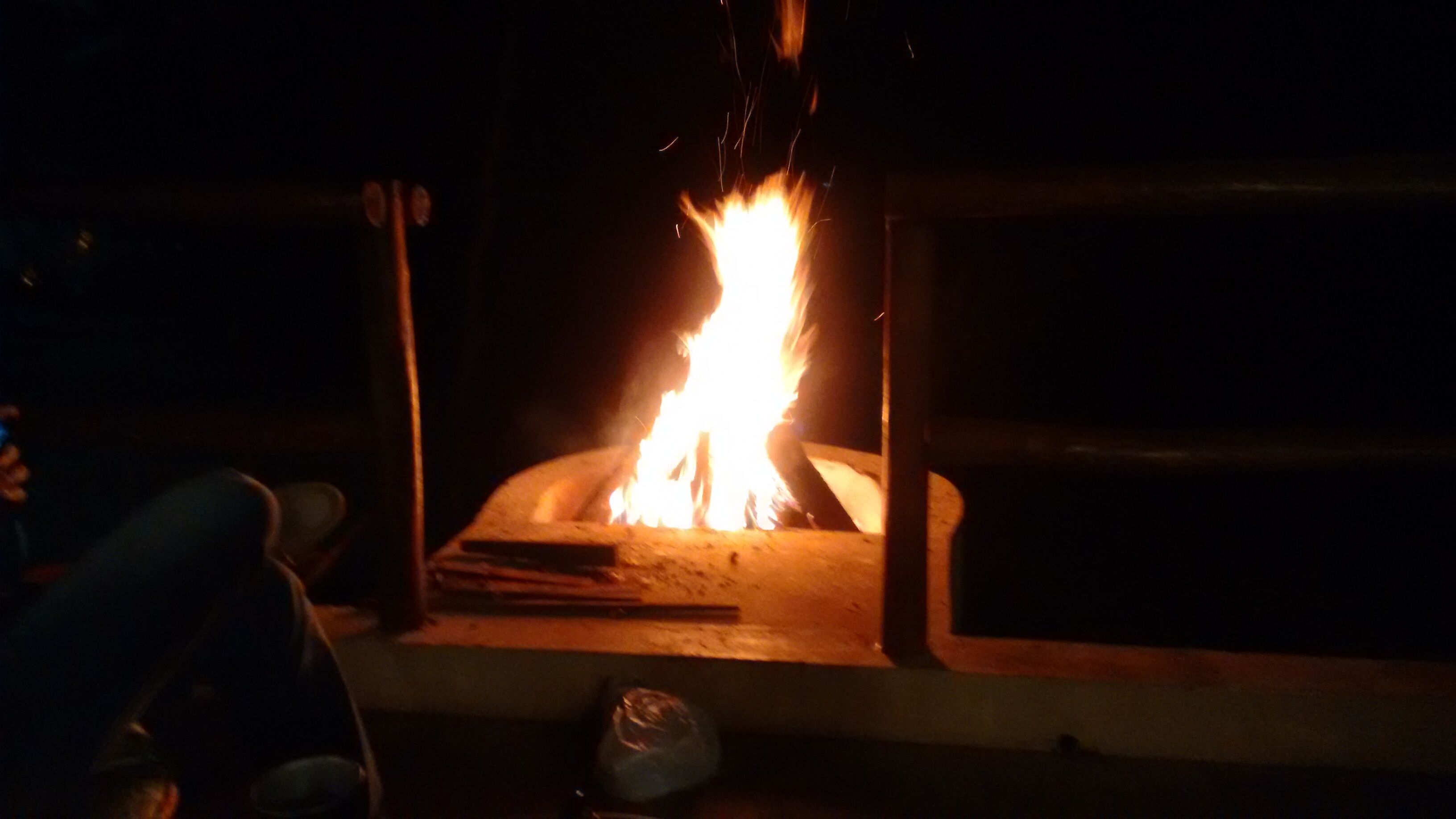 A fireplace with visible logs and a fire burning inside.