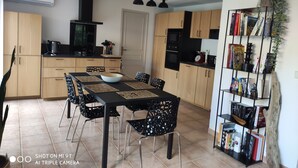 Eine moderne Küche mit Holzausstattung, einer schwarzen Arbeitsplatte und einem Essbereich mit schwarzen Stühlen und einer zentralen Kochinsel.