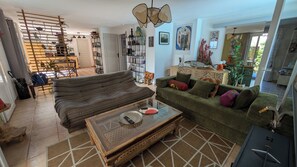 A living room with a sofa, a coffee table, and a bookshelf. - Villa with pool, close to the active downtown of Marseille (Marseillan)