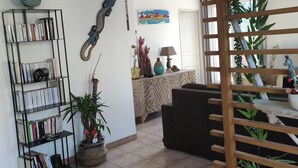 Ein Wohnzimmer mit Bücherregal, einer Couch, einer Holzkopfbaueruhe und einem Gemälde an der Wand.