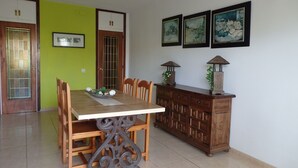 Un comedor con una mesa y sillas de madera, un mueble con adornos y tres cuadros en la pared.