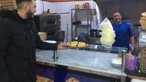 Una cocina con horno de pizza, estantes con utensilios y un mostrador con una pizza.