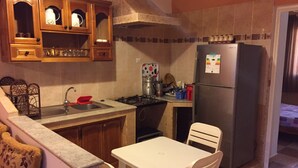 Cocina compacta con estufa a gas, pileta y refrigerador. Cuenta con una mesa de comedor y sillas.