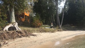 A sandy beach with a wooden structure and a tree with exposed roots. - Gorgeous Rustic Northern Michigan Island Getaway (St. James)