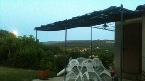 A covered patio area with white plastic chairs and a table, a potted plant, and a bicycle leaning against a wall. -  BASTIDON, POOL, 3000 M2 OF LAND, 2-4 PERS, APT, Luberon (Apt)