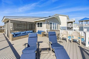 A deck with lounge chairs and a sofa, a pool, and a covered area with a balcony. - Van Divender | Oceanfront | Private Pool (Virginia Beach)