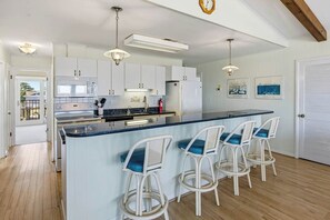 A kitchen with white cabinets, a central island with bar stools, and pendant lighting.