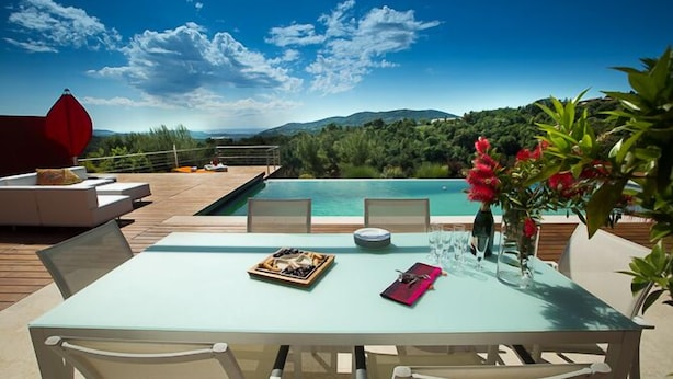A poolside dining area with a table set for two, overlooking a pool and a mountainous landscape. - SunlightProperties: SPLENDID: Villa, 4 Bedroom/ 3 bath, jacuzzi, heated pool (Peymeinade)